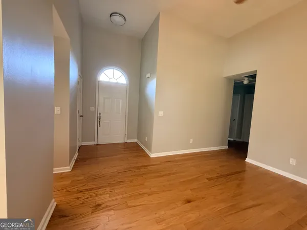 a view of empty room with wooden floor and fan