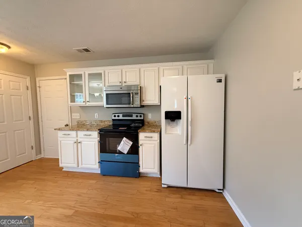 a view of kitchen and empty room with wooden floor