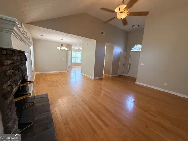 an empty room with wooden floor fireplace and windows