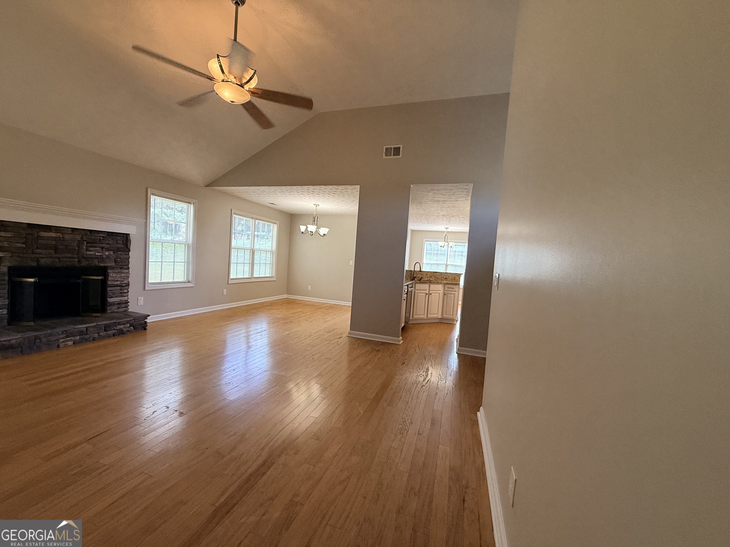 577 Pendergrass Road Winder, GA 30680 - Photo 10 of 25 an empty room with wooden floor fireplace and windows