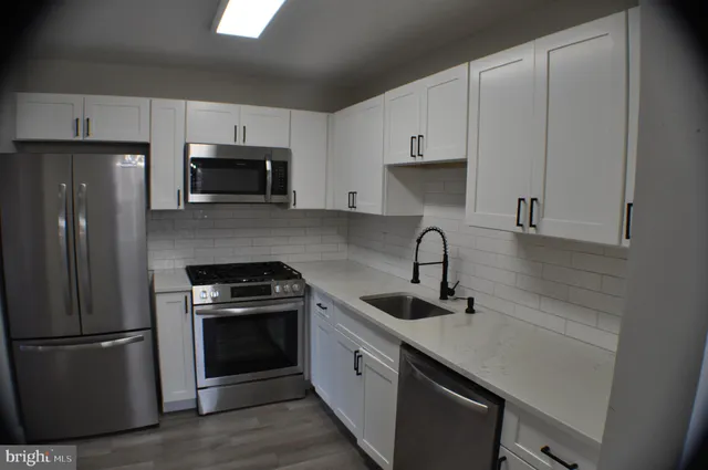 a kitchen with cabinets stainless steel appliances and sink