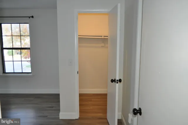 an empty room with wooden floor closet and windows
