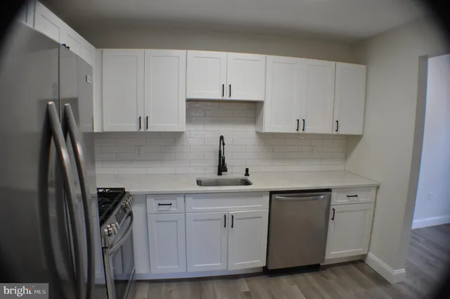a kitchen with white cabinets sink and refrigerator