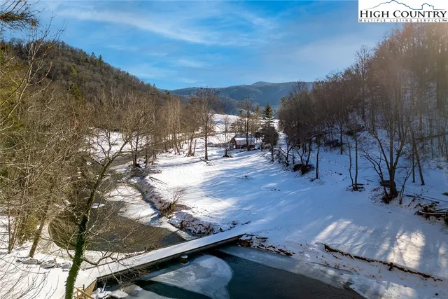 a view of a house with large trees and sitting area