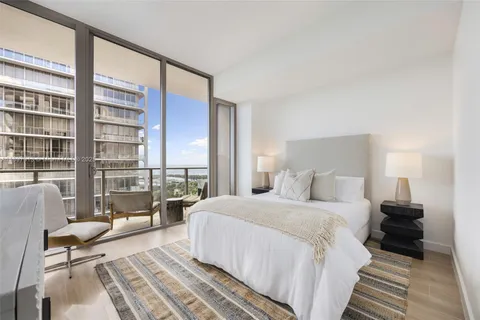 a bedroom with a bed and a large window with outer view