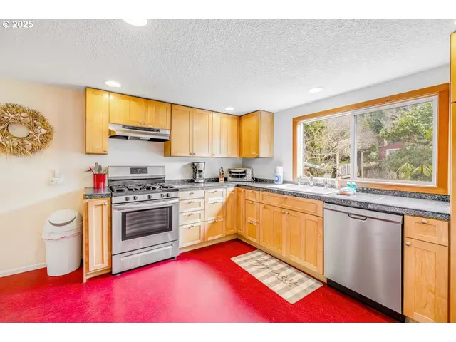 a kitchen with stainless steel appliances granite countertop a stove a sink and a microwave