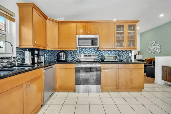 a kitchen with stainless steel appliances granite countertop a stove a sink and a microwave