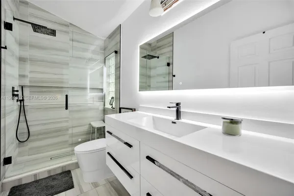 a bathroom with a sink a toilet and shower