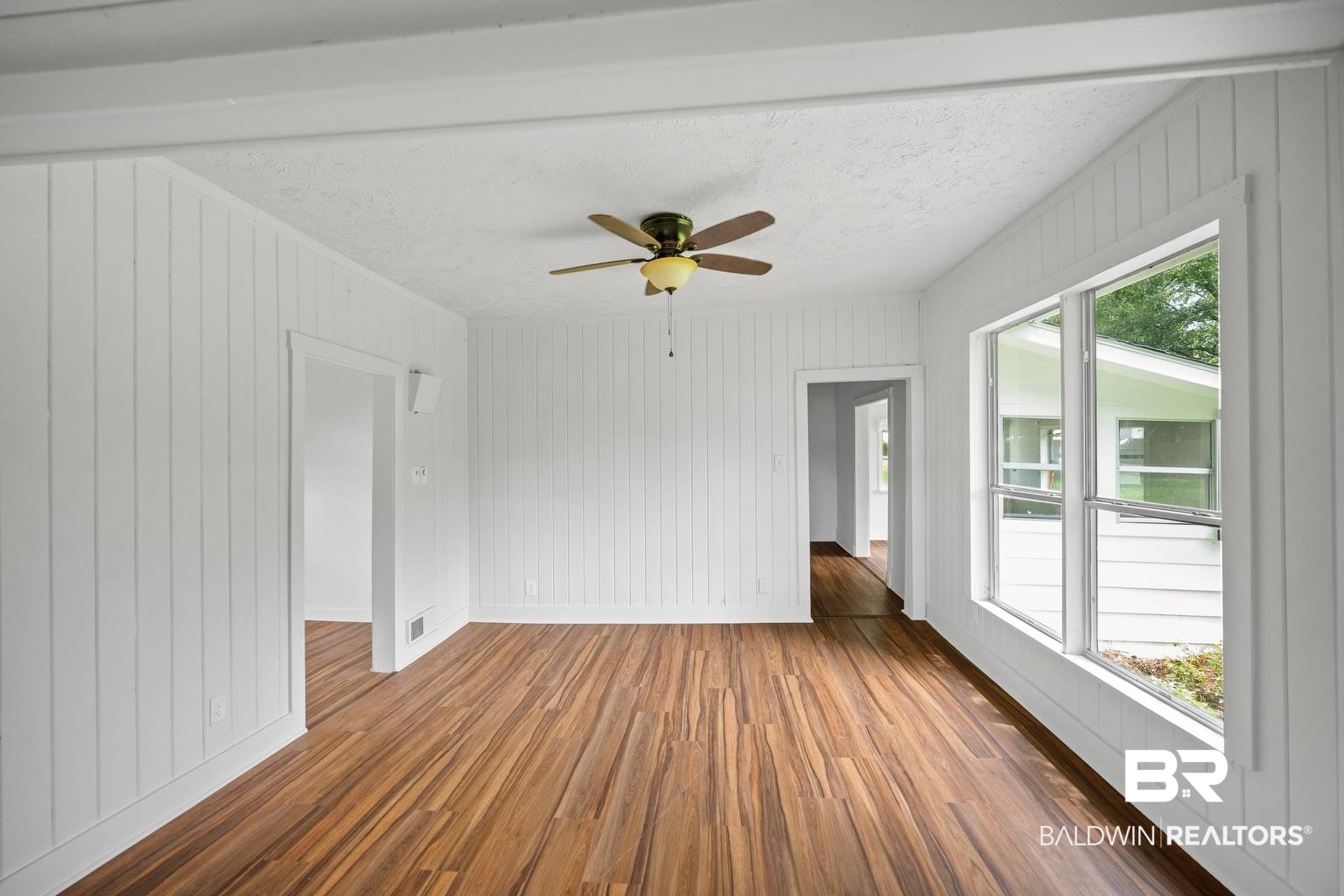 19575 Keller Road Foley, AL 36535 - Photo 5 of 17 Empty room featuring dark wood-style floors, wooden walls, ceiling fan, and a textured ceiling