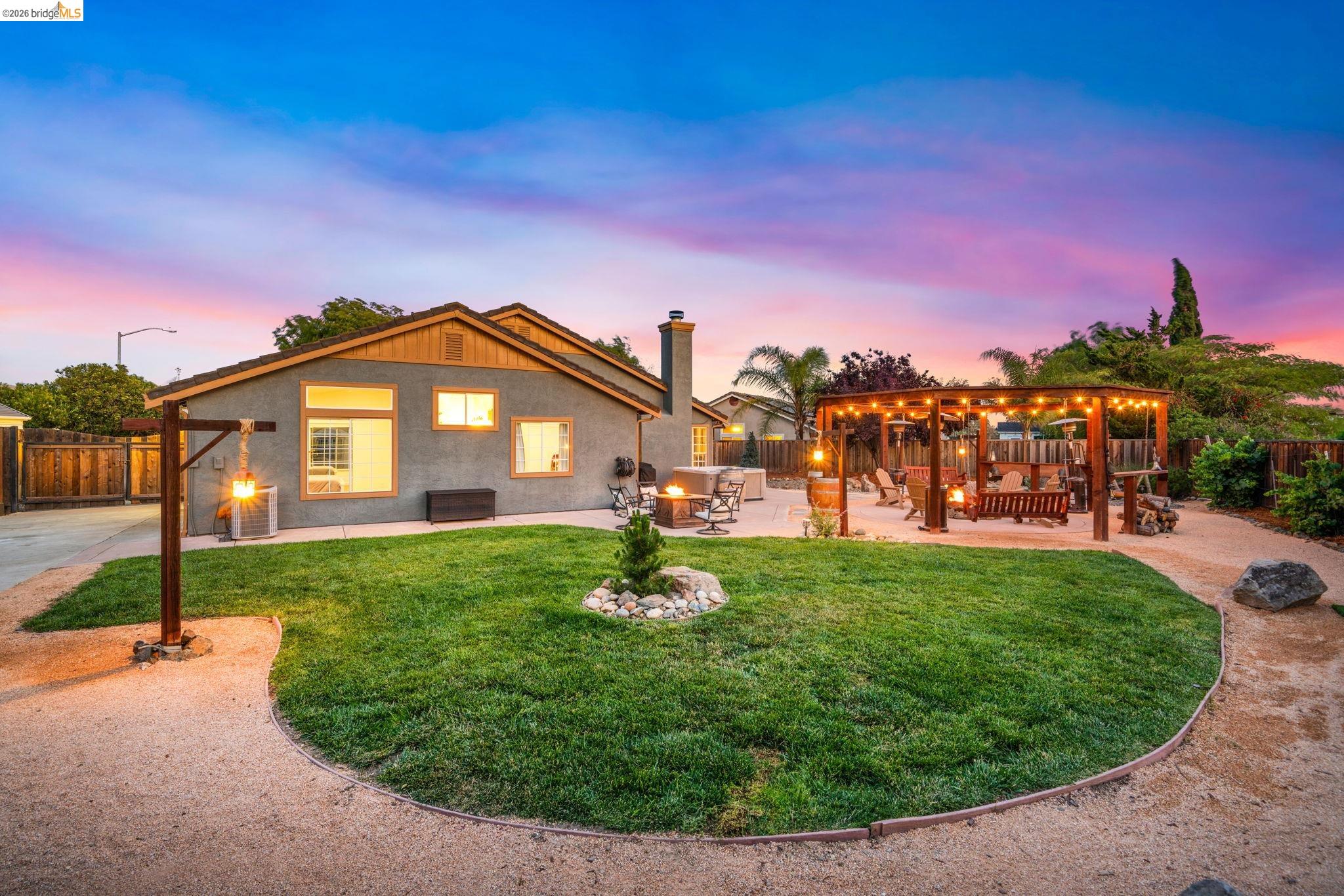 1186 El Rio Court Livermore, CA 94551 - Photo 47 of 60 Expansive backyard featuring a central lawn, gravel pathways, and a covered patio with string lights
