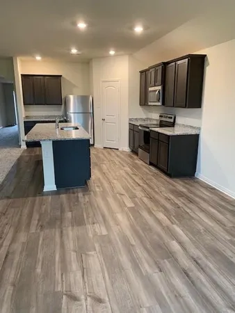 a large kitchen with stainless steel appliances kitchen island granite countertop a sink stove and refrigerator