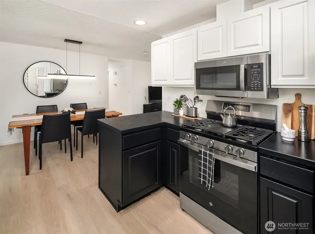 a kitchen with stainless steel appliances granite countertop a stove a sink a microwave and dining table