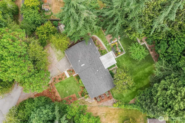 an aerial view of a house with a yard and trees all around