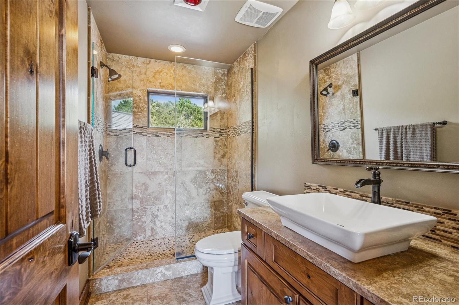 477 West Meadow Road Evergreen, CO 80439 - Photo 25 of 50 a bathroom with a granite countertop sink a toilet a mirror and shower