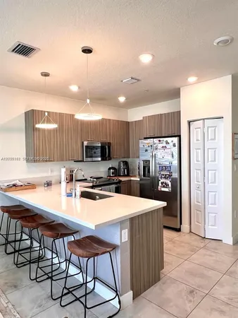 a kitchen with stainless steel appliances a stove a refrigerator a kitchen island and chairs