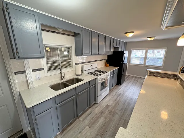 a kitchen with granite countertop a sink stove and refrigerator