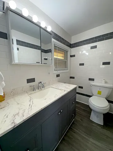 a bathroom with a granite countertop sink mirror vanity and toilet