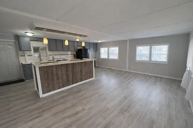a view of kitchen with stainless steel appliances wooden floor and window