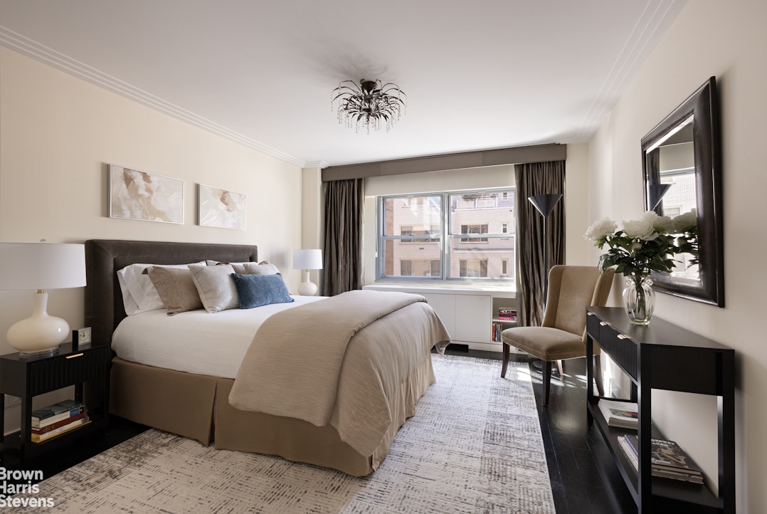 27 East 65th Street, Unit 11D Manhattan, NY 10065 - Photo 10 of 15 a spacious bedroom with a bed a mirror and a large window with balcony view