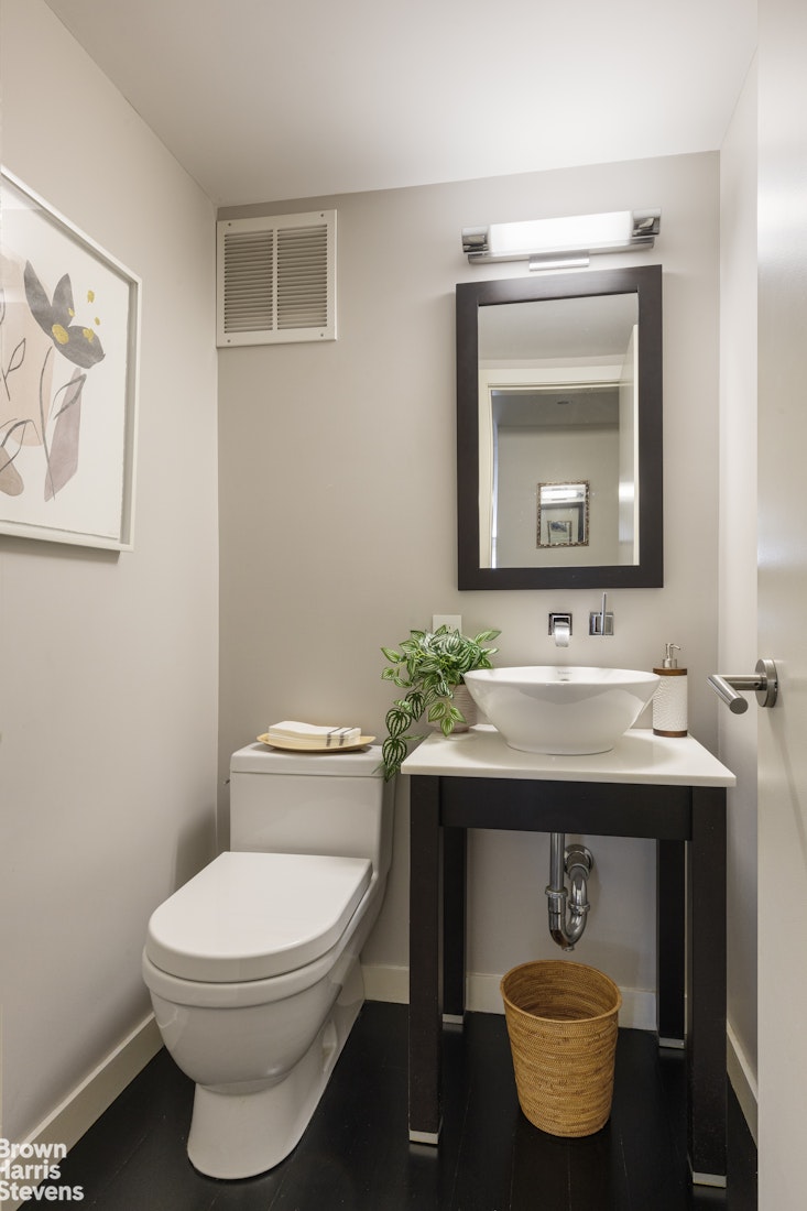 27 East 65th Street, Unit 11D Manhattan, NY 10065 - Photo 12 of 15 a bathroom with a toilet a sink and mirror