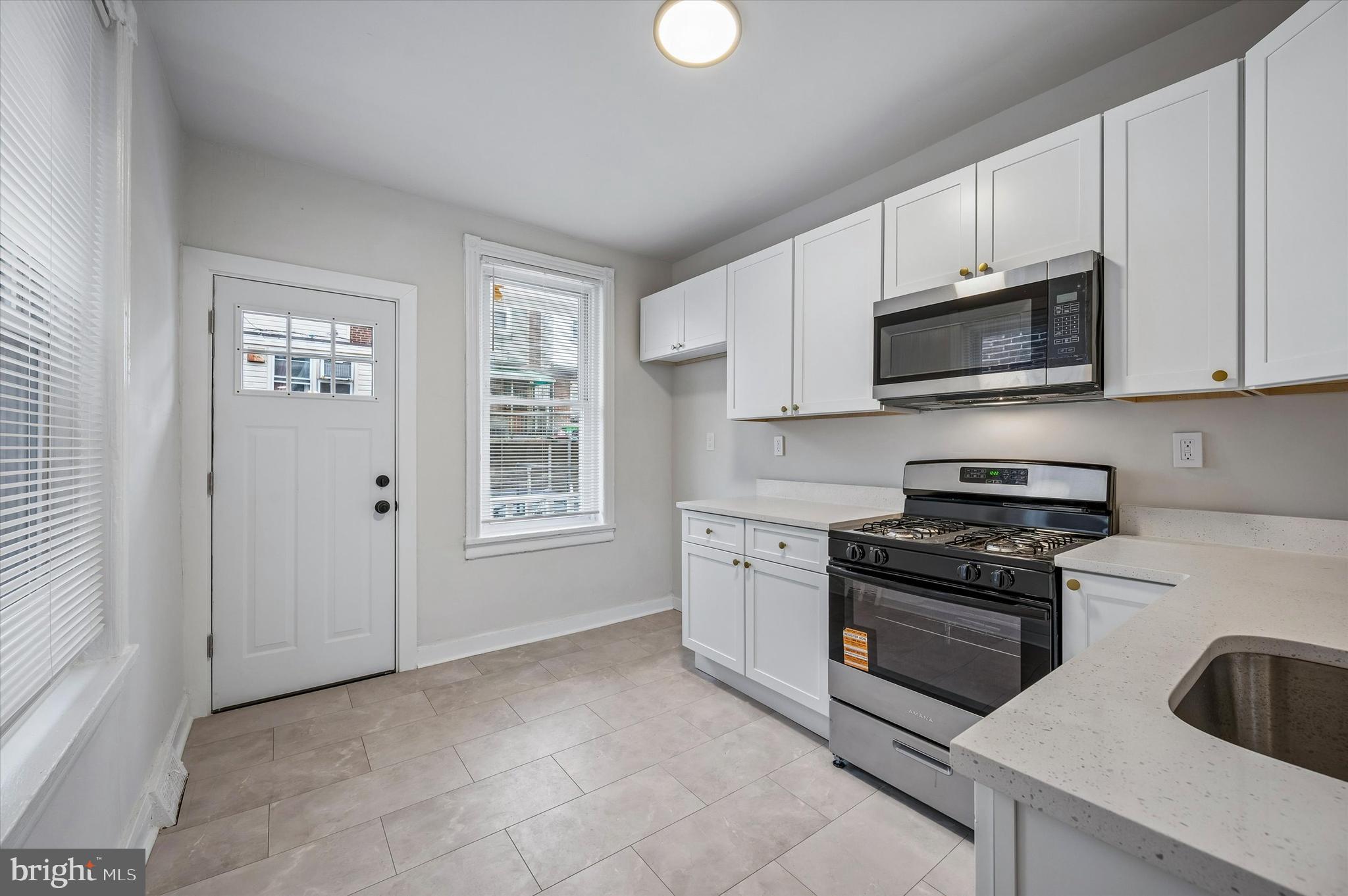 2433 South Millick Street Philadelphia, PA 19142 - Photo 7 of 15 a kitchen with granite countertop white cabinets and stainless steel appliances