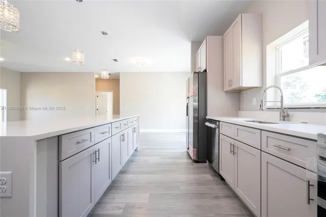 a kitchen with white cabinets appliances and a window