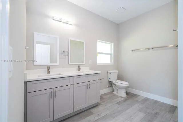 a bathroom with a toilet a sink a mirror and a window