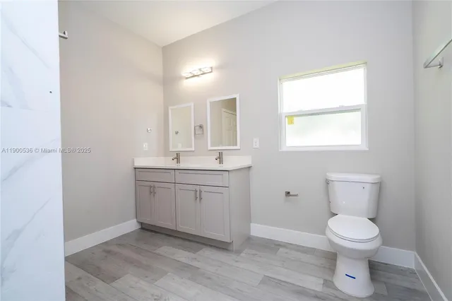 a bathroom with a toilet a sink a mirror and a window