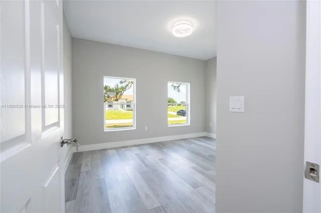 an empty room with window and wooden floor