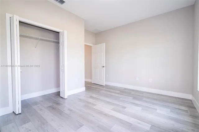 an empty room with wooden floor & closet area