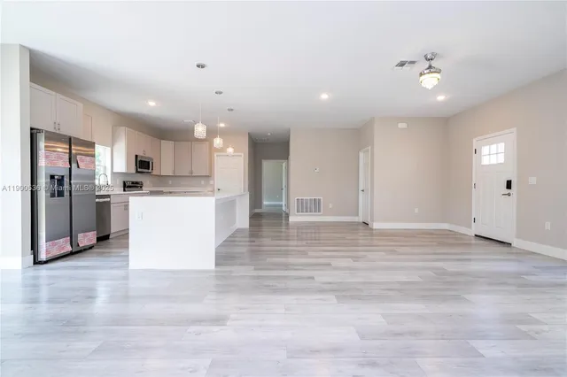 a view of kitchen with kitchen island a sink stainless steel appliances and cabinets