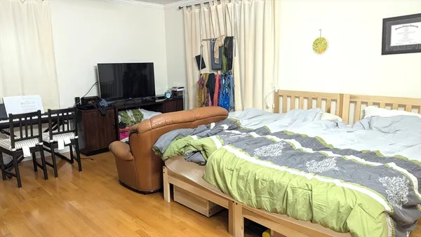 a bedroom with bed and a flat tv screen on dresser