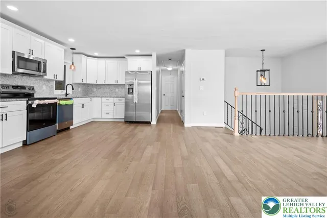 an empty room with wooden floor chandelier fan and windows