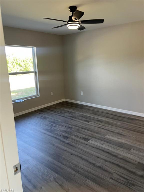 374 Compese Avenue South Lehigh Acres, FL 33974 - Photo 5 of 15 an empty room with wooden floor a ceiling fan and windows