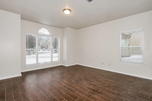 an empty room with wooden floor and windows