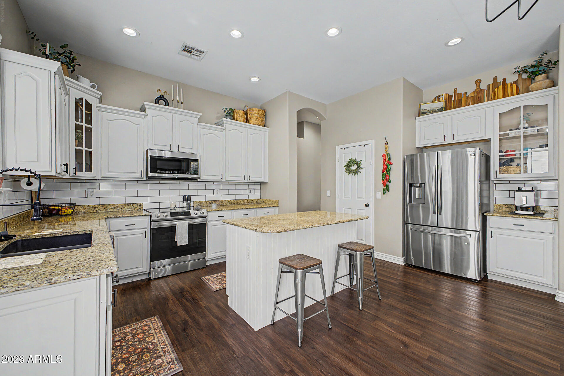 2065 South Porter Street Gilbert, AZ 85295 - Photo 15 of 36 a kitchen with a refrigerator a stove top oven a sink dishwasher a dining table and chairs with wooden floor