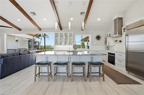 a kitchen with stainless steel appliances kitchen island granite countertop a table chairs sink and cabinets