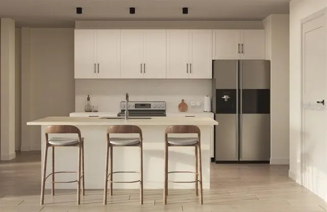a kitchen with stainless steel appliances kitchen island granite countertop a table chairs and white cabinets