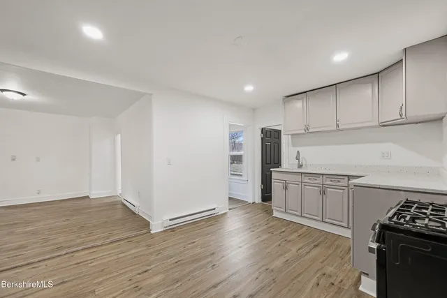 a kitchen with granite countertop a stove top oven a sink dishwasher and a refrigerator with wooden floor