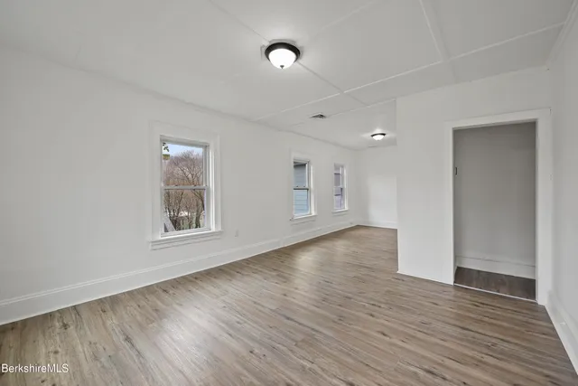 a view of an empty room with wooden floor and a window