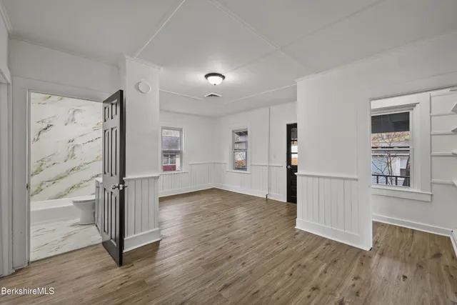 an empty room with wooden floor and a kitchen