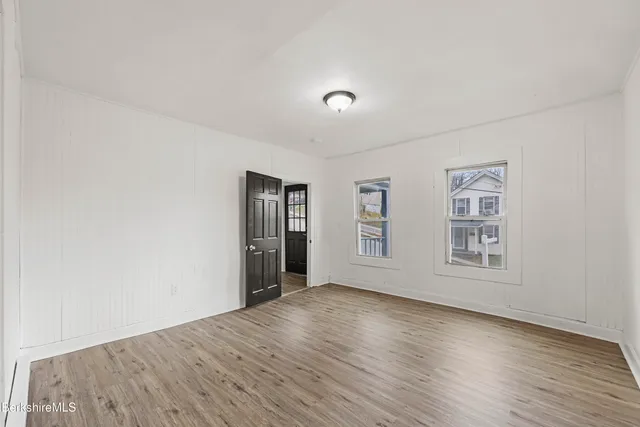 an empty room with wooden floor and windows