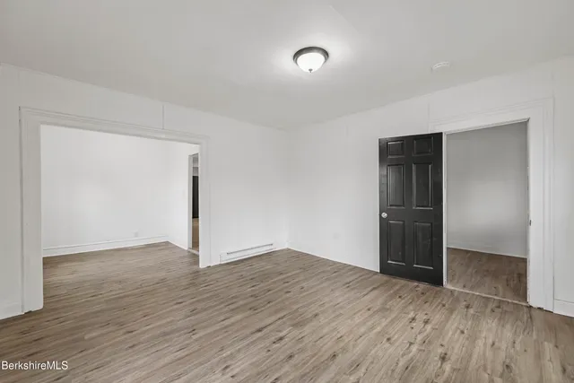an empty room with wooden floor & closet and natural light