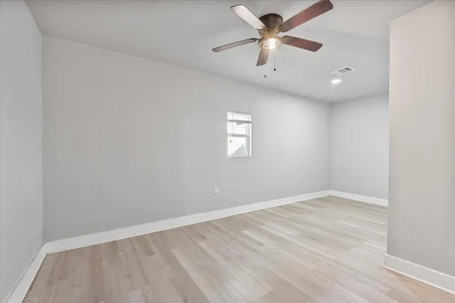 an empty room with windows and fan