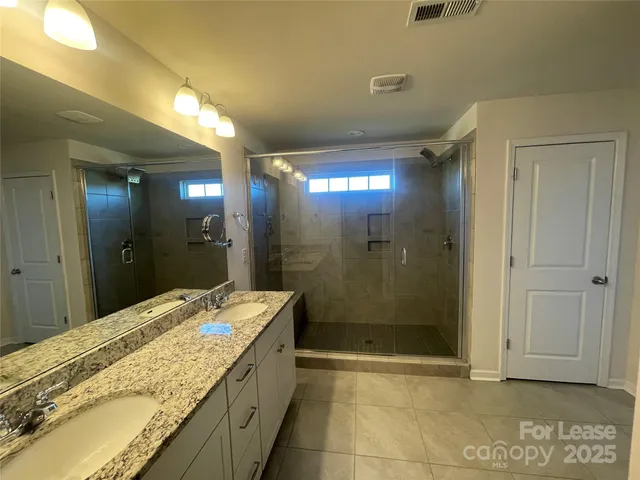 a bathroom with a granite countertop sink a shower and a mirror