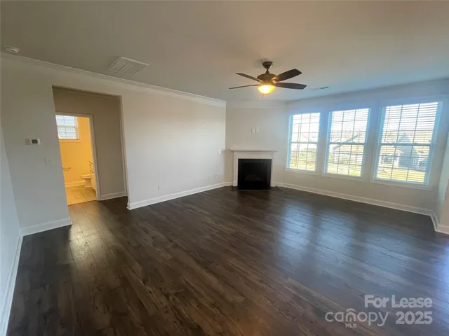 a view of an empty room with window and wooden floor