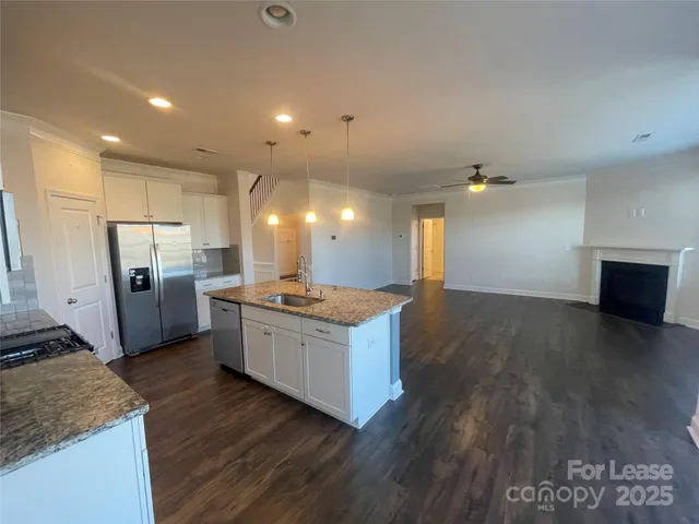 a large kitchen with a stove a sink dishwasher a refrigerator and wooden floor