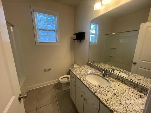 a bathroom with a granite countertop sink a toilet and mirror
