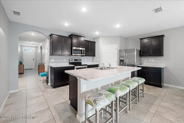 a large kitchen with cabinets chairs stainless steel appliances and a counter space
