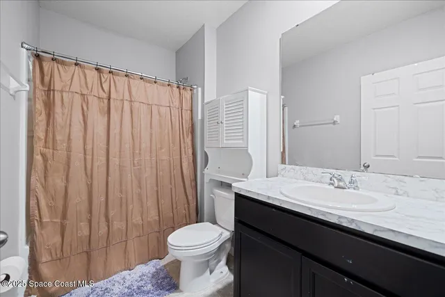 a bathroom with a sink a toilet and shower curtain